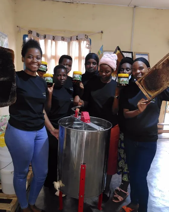 Our team holding honeycomb frames and honey jars around a honey extractor